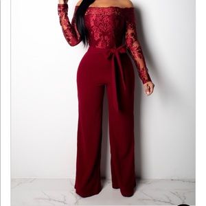 Red off shoulder jumpsuit w/ lace flower sleeves.